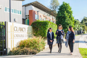Mother walking with her daughters in front of Clancy Catholic College West Hoxton