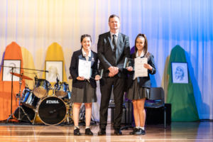 principal with 2 students on stage